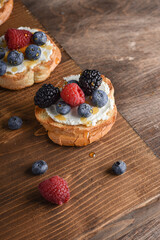 Bruschetta with cream cheese and berries on the wooden table. Close up. Copy space