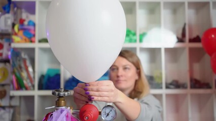 a woman inflates of helium from a white balloon.