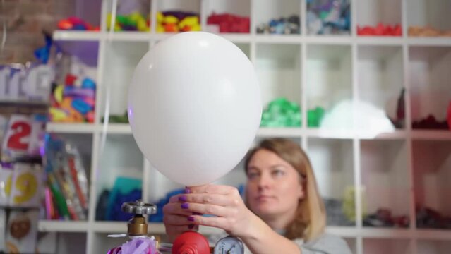 a woman inflates of helium from a white balloon.