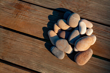 Group of pebble stones on wooden surface of pier in summer. Beach, sea, zen, spa, summer, relax concept. 