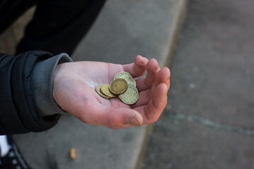 closeup of euros coins in hand of poor man sitting in the street