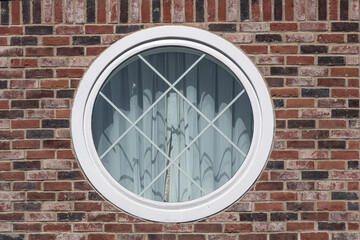 White framed circular window set in a red brick wall