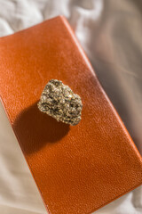 pyrite, fool's gold mineral on brown field guide book in the sunlight