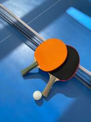 Tennis rackets and ball lie on a blue tennis table, top view. Ping pong rackets with a ball