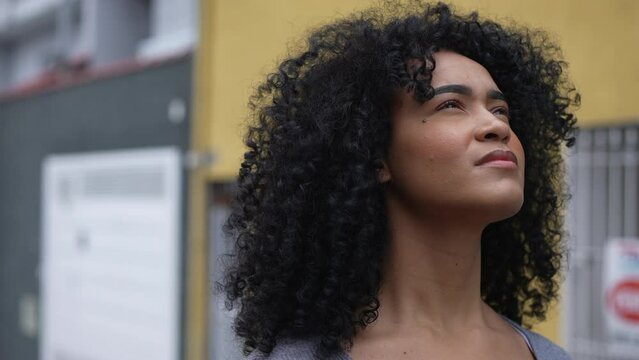 A latina black woman looking at sky with eyes closed feeling hopeful
