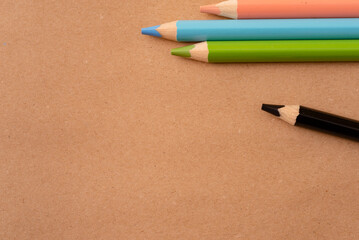 School, education and art concept with colorful pencils on natural recycled paper background.