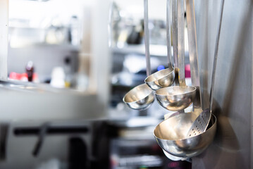Several ladles stacked on a shelf in a professional restaurant kitchen prior to service. chef
