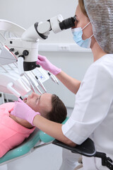 A man at a dentist's appointment. Dental examination and treatment under a microscope. Modern dentistry. Prevention of dental diseases.Vertical photo.