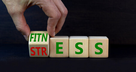 Fitness or stress symbol. Doctor turns the wooden cube and changes the word Stress to Fitness. Beautiful grey table grey background. Medical, psychological, fitness or stress concept. Copy space.