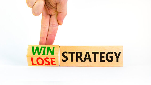 Win-lose strategy symbol. Businessman turns wooden cubes and changes words lose strategy to win strategy. Beautiful white table, white background. Business, win-lose strategy concept. Copy space.