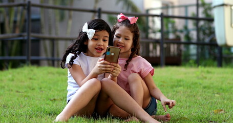 Children addicted to cellphone, two little girls looking at smartphone device on social media