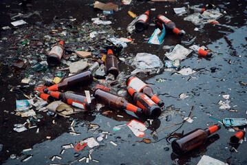 A large pile of household garbage on the sidewalk. Used glass bottles and paper packaging are lying...