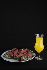 strawberries with a glass of juice on a black background