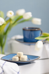 Still life with white candies and white tulips on background