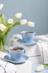 Fototapeta na wymiar Still life with blue cups of tea and white tulips on background