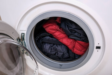 Dirty clothes of different colors in a washing machine drum, laundry concept