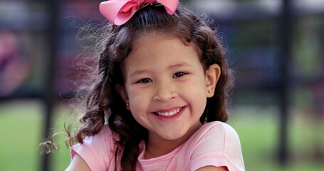 Charming diverse little girl child close-up face portrait smiling outside