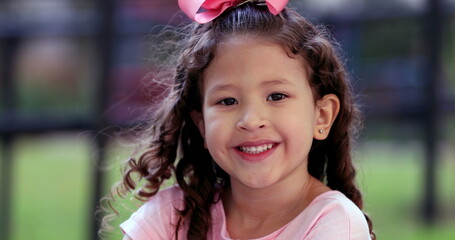 Charming diverse little girl child close-up face portrait smiling outside