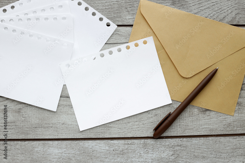 Poster top view of wooden office table with supplies and blank paper and envelope in the middle. view from 