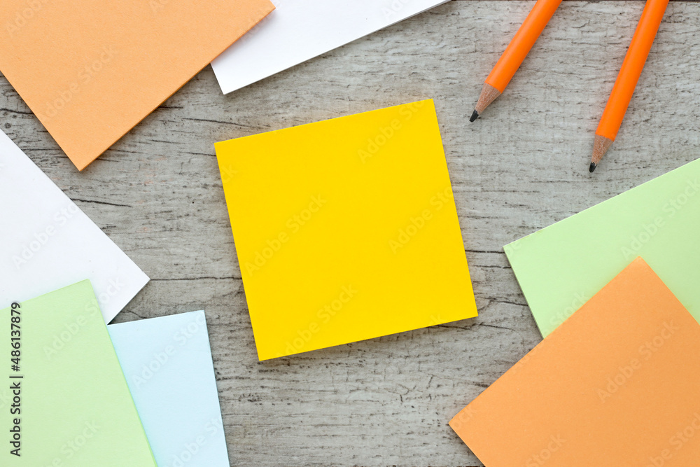 Poster sticky note on wood table.next to pencils and a notepad with a spring on the table.space for your te