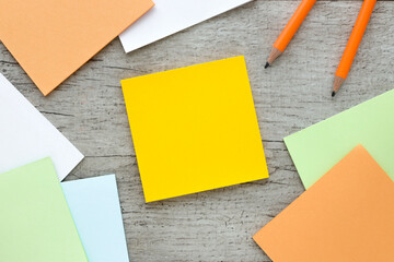 Sticky note on wood table.next to pencils and a notepad with a spring on the table.space for your text
