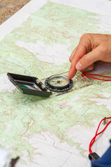 Using a paper map and compass to plot a course of navigation while hiking.