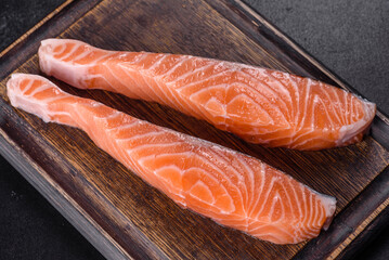 Fresh salmon fillets on black cutting board with herbs and spices