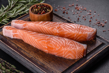 Fresh salmon fillets on black cutting board with herbs and spices