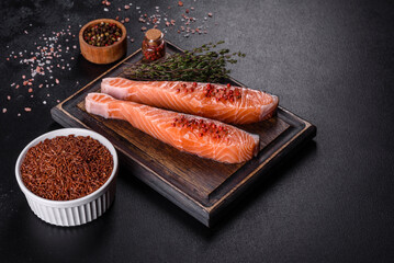 Fresh salmon fillets on black cutting board with herbs and spices