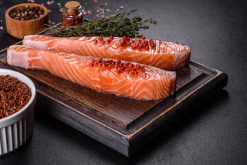 Fresh salmon fillets on black cutting board with herbs and spices