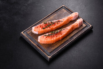 Fresh salmon fillets on black cutting board with herbs and spices