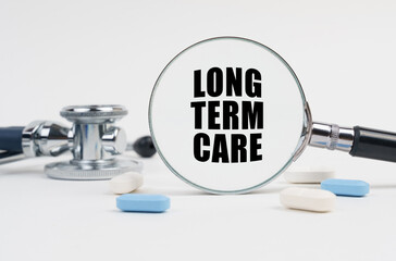On a white surface lie pills, a stethoscope and a magnifying glass with the inscription - LONG TERM...