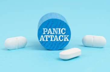 Pills lie on a blue surface, a wooden blue cylinder with the inscription - PANIC ATTACK