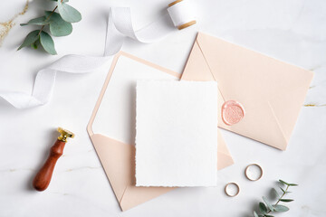 Wedding card mockup and wedding stationery on stone table. Pastel pink wedding envelopes, gold