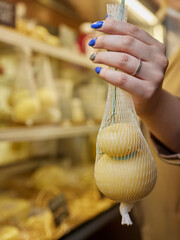 Delicious fresh Caciocavallo and Scamorza cheese hanging. Italian cheeses close up. The cheeses are...