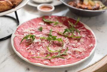 Traditional Beef Carpaccio Garnished with Parmesan Cheese and Fresh Arugula Leaves