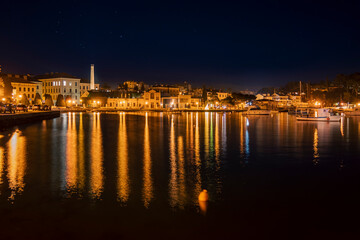 Fototapeta na wymiar Nightfall over Rovinj town port with old industrial architecture visible across the bayNightfall over Rovinj town port with old industrial architecture visible across the bay