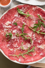 Traditional Beef Carpaccio Garnished with Parmesan Cheese and Fresh Arugula Leaves