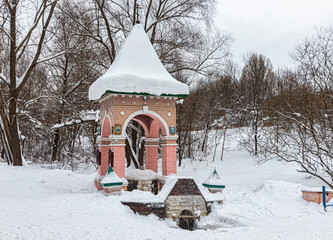 Naklejka premium Chapel with a snow-covered dome, near a spring, in a wooded area