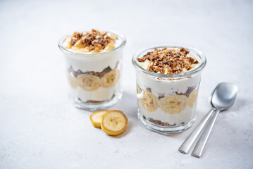 Banana Greek yogurt chocolate granola parfait in a glass
