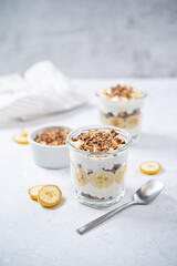 Banana Greek yogurt chocolate granola parfait in a glass
