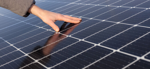 Close-up of woman's hand and solar panels. Concept: renewable energy, technology, electricity. Copy...