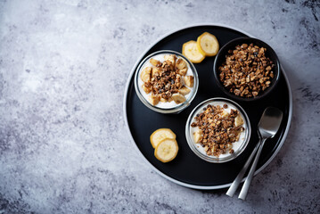Banana Greek yogurt chocolate granola parfait in a glass