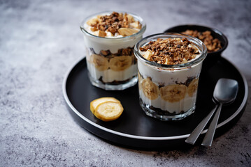 Banana Greek yogurt chocolate granola parfait in a glass