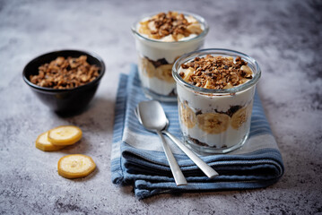 Banana Greek yogurt chocolate granola parfait in a glass