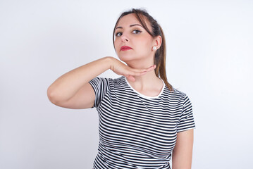 young Arab woman wearing striped t-shirt over white background cutting throat with hand as knife, threaten aggression with furious violence.