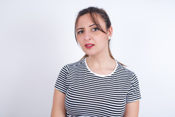 young Arab woman wearing striped t-shirt over white background Pointing down with fingers showing advertisement, surprised face and open mouth
