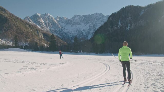The panoramic view of the cross country ski trail in the mountain foothills and cross country skiers, enjoying the sport on a beautiful sunny winter day.