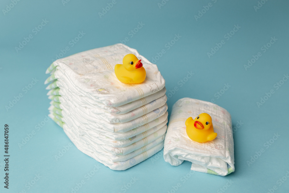 Wall mural baby disposable diapers on a blue background in a stack and a rubber duckling, copy space for text