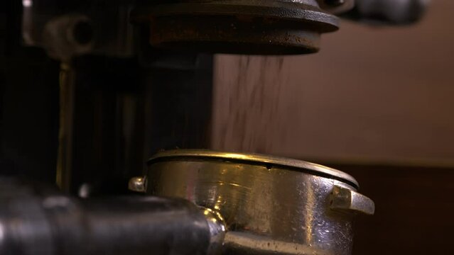 Barista using coffee machine to press coffee beans. Grounded espresso pouring in to a coffee tamper.